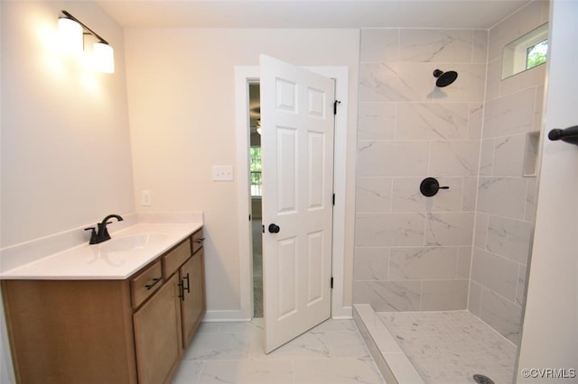 bathroom with vanity, marble finish floor, baseboards, and tiled shower