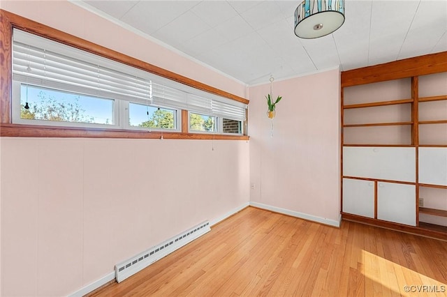 spare room with crown molding, a baseboard heating unit, and light hardwood / wood-style flooring