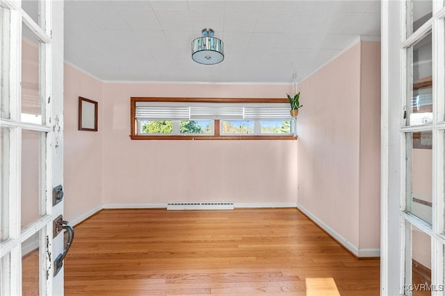 empty room with light hardwood / wood-style flooring, ornamental molding, and a baseboard radiator