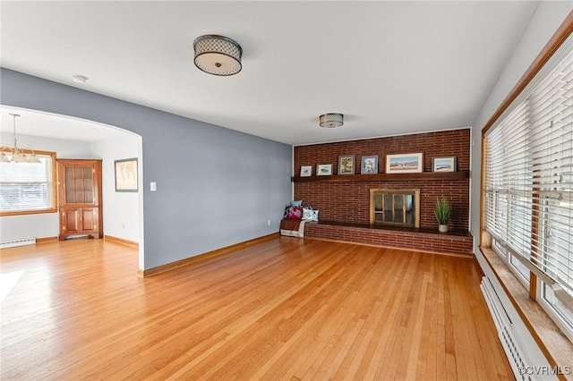 unfurnished living room with a baseboard radiator, a fireplace, and light hardwood / wood-style floors