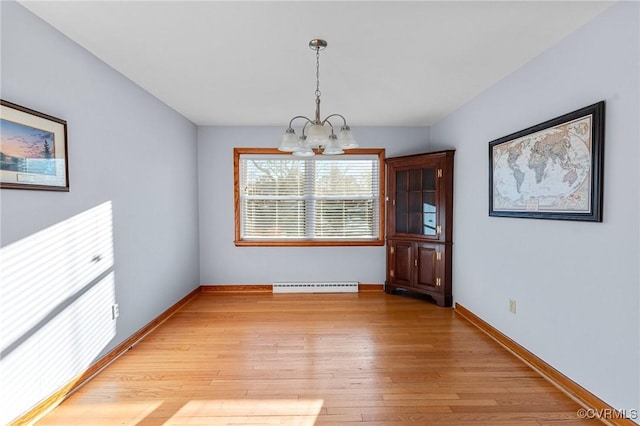 unfurnished dining area featuring an inviting chandelier, baseboard heating, and light wood-type flooring