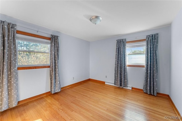 unfurnished room with plenty of natural light, hardwood / wood-style floors, and a baseboard heating unit