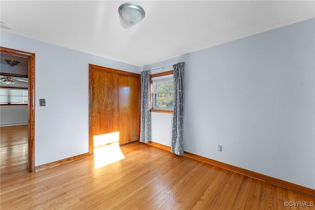 unfurnished bedroom featuring a baseboard heating unit and light hardwood / wood-style floors