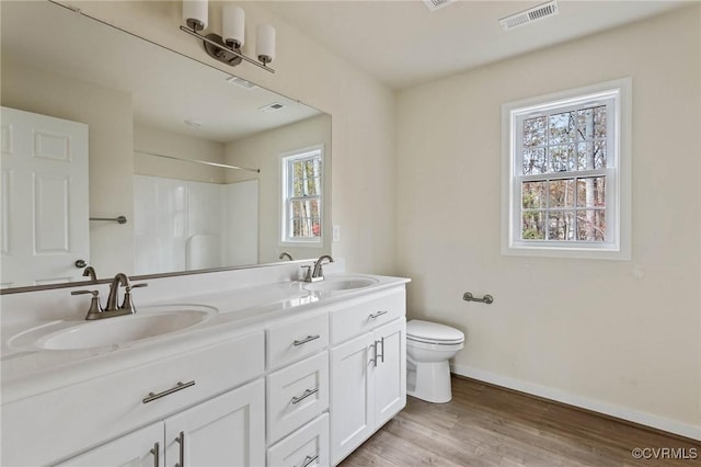 bathroom with vanity, wood-type flooring, a shower, and toilet