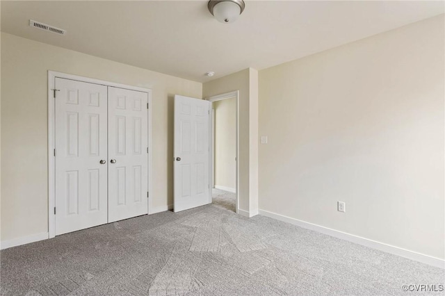 unfurnished bedroom with light colored carpet and a closet