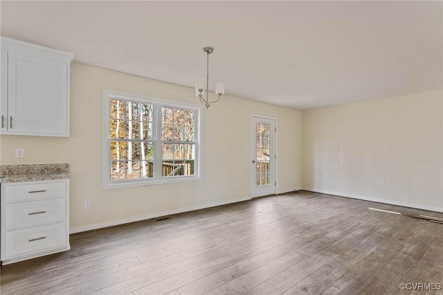 unfurnished dining area with a chandelier and hardwood / wood-style floors