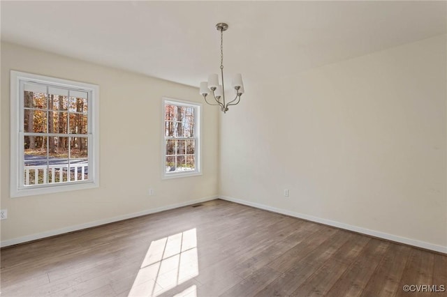 unfurnished room with wood-type flooring and a notable chandelier