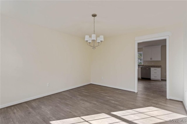 spare room featuring a notable chandelier and hardwood / wood-style flooring