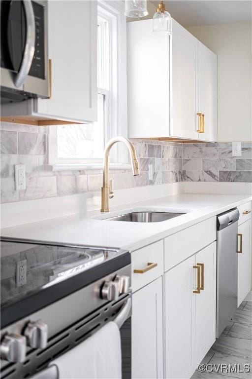 kitchen with stainless steel appliances, sink, white cabinets, and decorative backsplash