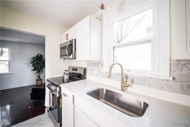 kitchen with sink, backsplash, white cabinets, and appliances with stainless steel finishes