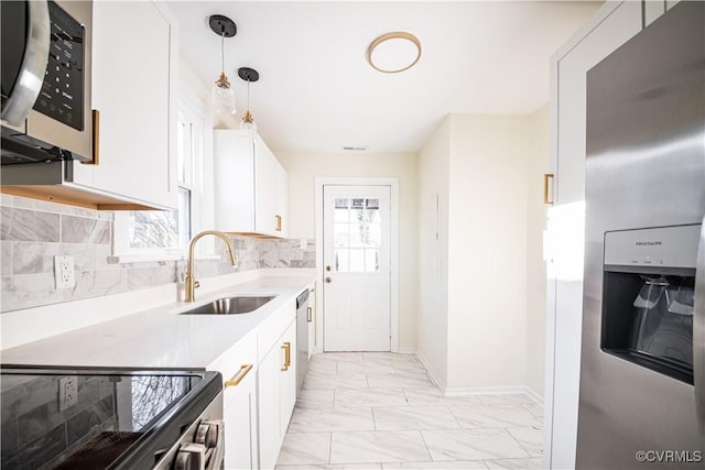 kitchen with appliances with stainless steel finishes, decorative light fixtures, sink, white cabinets, and backsplash