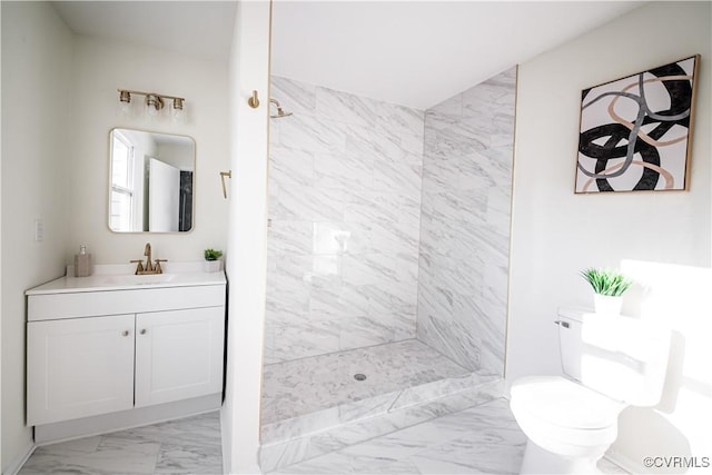 bathroom featuring a tile shower, vanity, and toilet