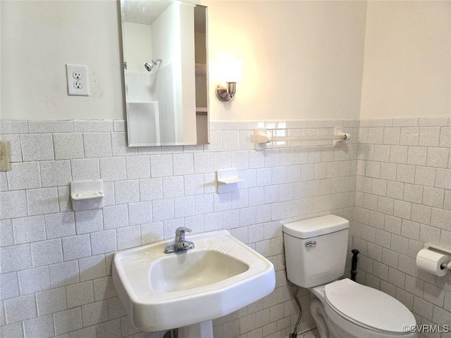 bathroom featuring toilet, sink, and tile walls