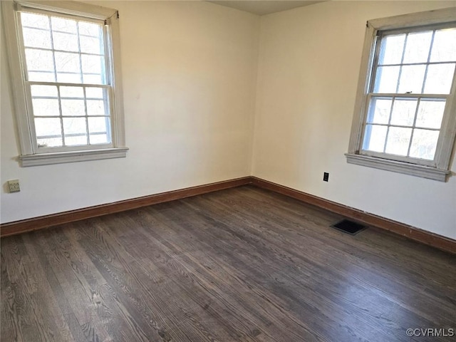 unfurnished room with a healthy amount of sunlight and dark hardwood / wood-style flooring