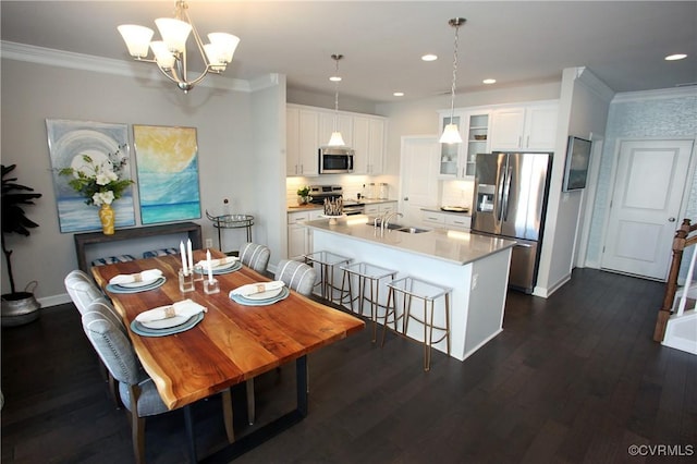 dining area featuring dark hardwood / wood-style flooring, sink, ornamental molding, and a chandelier