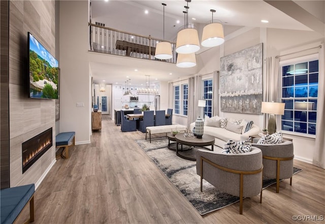 living room featuring hardwood / wood-style flooring, a tile fireplace, and a high ceiling