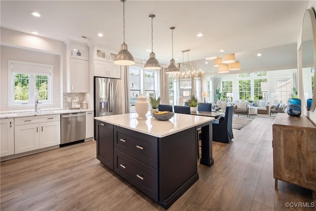 kitchen featuring pendant lighting, sink, stainless steel appliances, a center island, and white cabinets