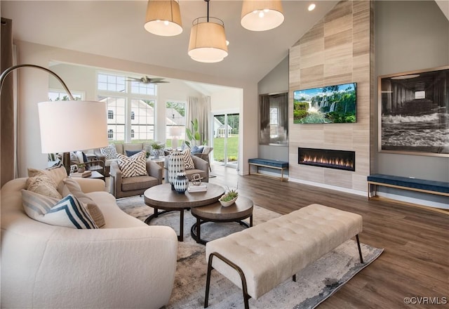 living room with dark wood-type flooring, a tiled fireplace, and high vaulted ceiling