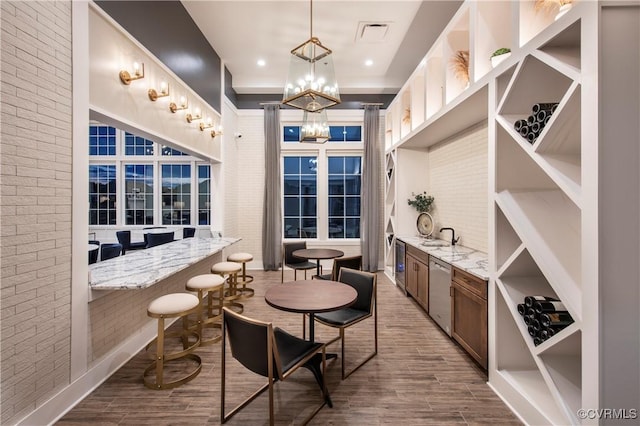 interior space with sink, wood-type flooring, a chandelier, and brick wall