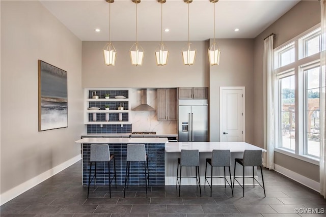 kitchen with wall chimney exhaust hood, appliances with stainless steel finishes, a large island, and hanging light fixtures