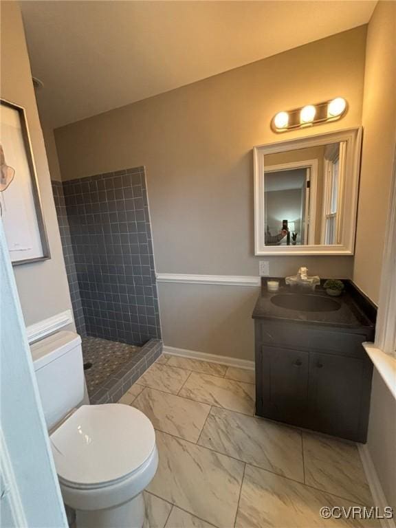 bathroom featuring vanity, toilet, and a tile shower