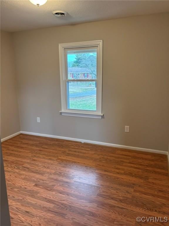 unfurnished room with dark wood-type flooring and a textured ceiling