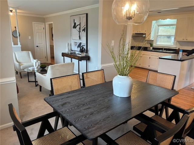 dining space with crown molding, sink, a notable chandelier, and light hardwood / wood-style flooring