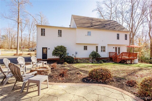 back of property featuring a wooden deck, a patio, and a fire pit