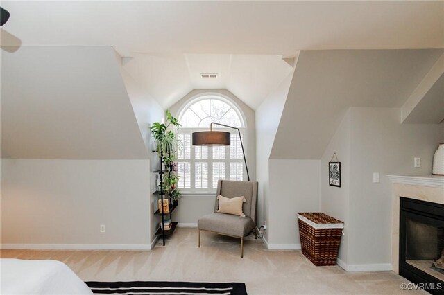 carpeted bedroom with vaulted ceiling and a high end fireplace