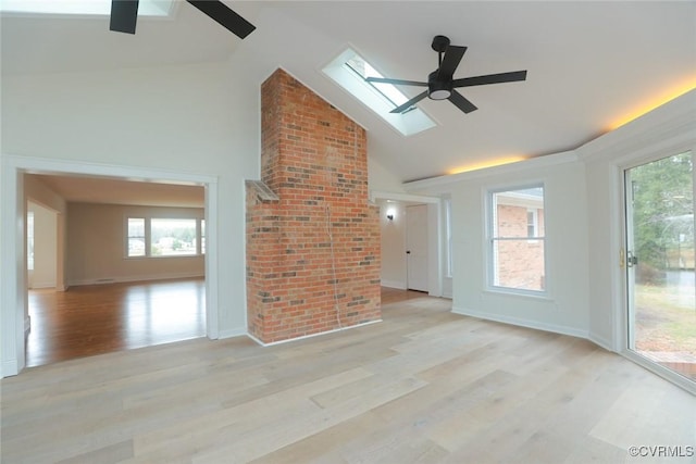 empty room featuring ceiling fan, high vaulted ceiling, a skylight, and light hardwood / wood-style flooring