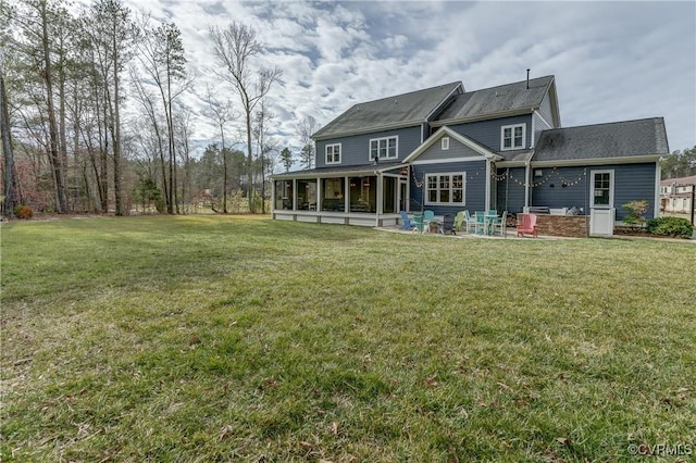 rear view of property featuring a sunroom, a patio area, and a lawn