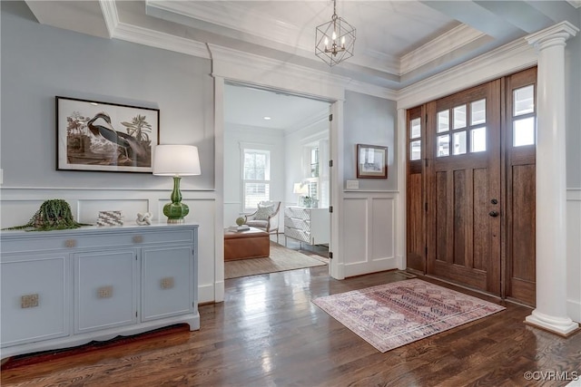 foyer with dark wood-type flooring, ornamental molding, and decorative columns