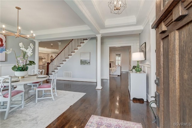 entrance foyer featuring ornate columns, ornamental molding, dark hardwood / wood-style floors, and an inviting chandelier