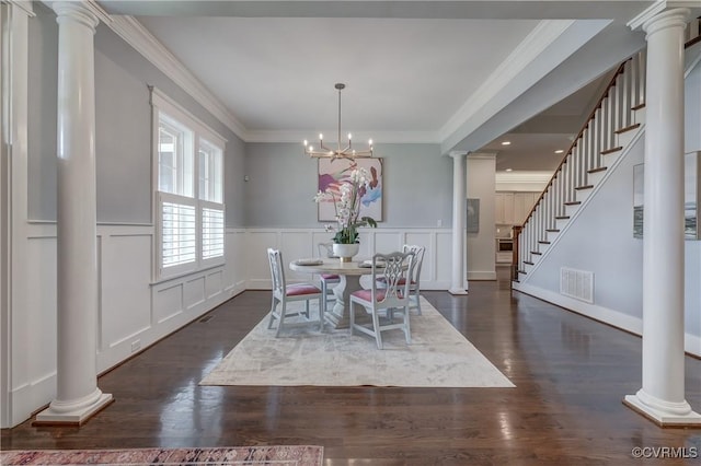 dining area with decorative columns, crown molding, dark wood-type flooring, and an inviting chandelier