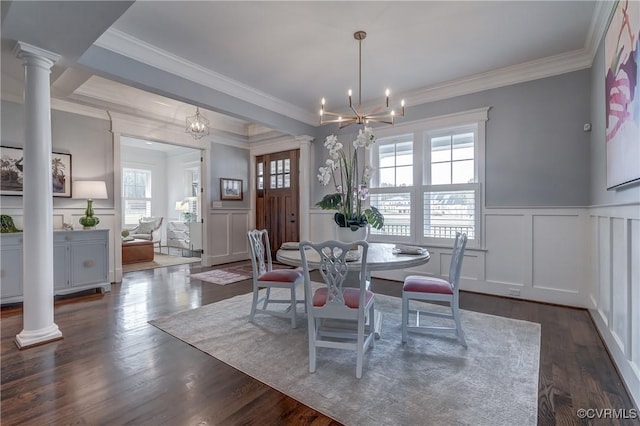 dining room with ornate columns, crown molding, dark wood-type flooring, and a chandelier