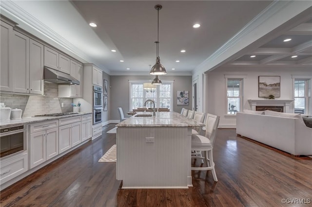 kitchen with pendant lighting, an island with sink, a breakfast bar area, decorative backsplash, and light stone counters