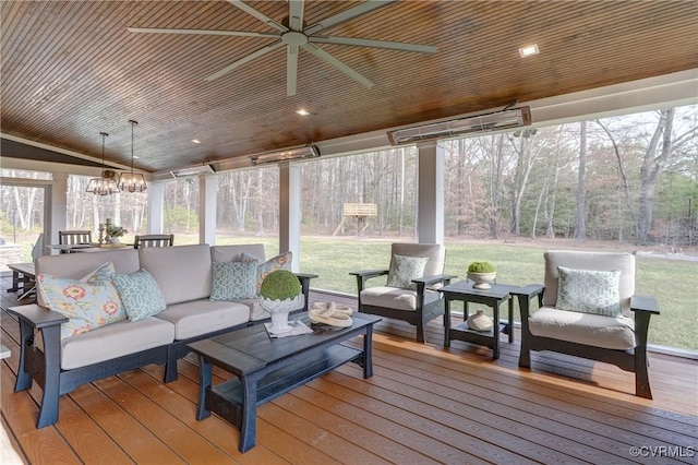 sunroom / solarium featuring ceiling fan with notable chandelier, plenty of natural light, and vaulted ceiling