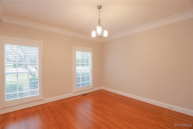 unfurnished room featuring an inviting chandelier, hardwood / wood-style floors, and crown molding