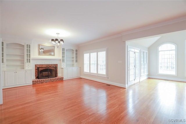 unfurnished living room with a brick fireplace, ornamental molding, a chandelier, and light wood-type flooring