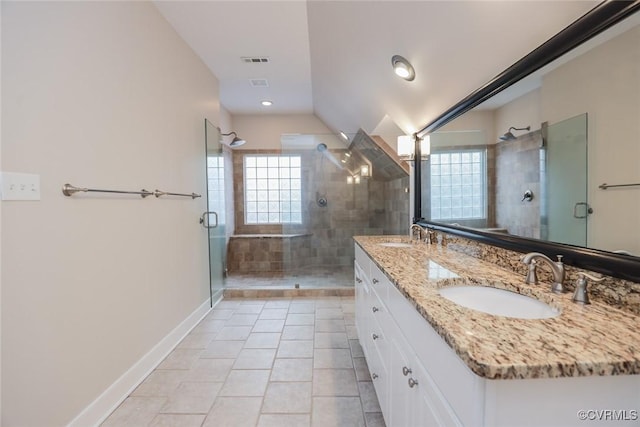 bathroom with tile patterned flooring, vanity, a wealth of natural light, and walk in shower