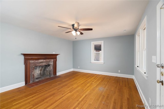 unfurnished living room featuring ceiling fan, a brick fireplace, and light hardwood / wood-style floors