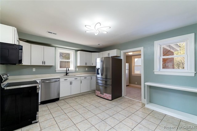 kitchen with sink, stainless steel appliances, white cabinets, and light tile patterned flooring