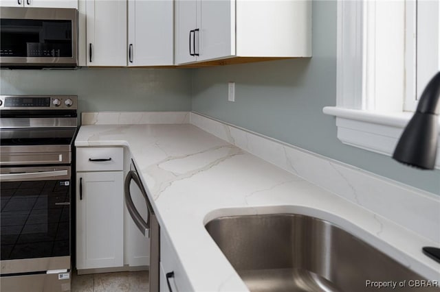 kitchen featuring light stone countertops, white cabinets, and appliances with stainless steel finishes