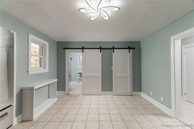 tiled spare room featuring a barn door