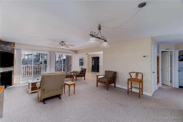 living room with a stone fireplace, carpet flooring, and ceiling fan