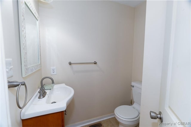 half bath featuring vanity, toilet, tile patterned flooring, and baseboards