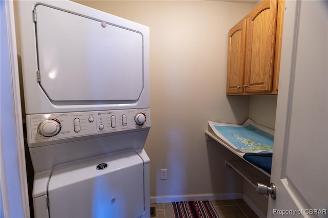 laundry room with cabinets, stacked washer / dryer, and tile patterned flooring