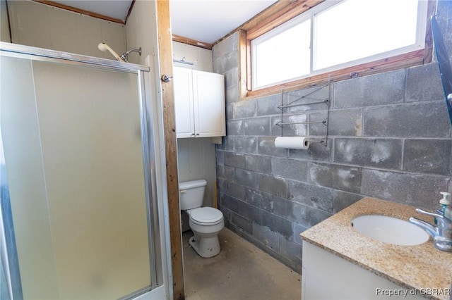 bathroom with a shower with door, vanity, concrete floors, and toilet