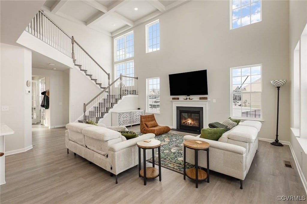 living room featuring beamed ceiling, coffered ceiling, and light hardwood / wood-style flooring