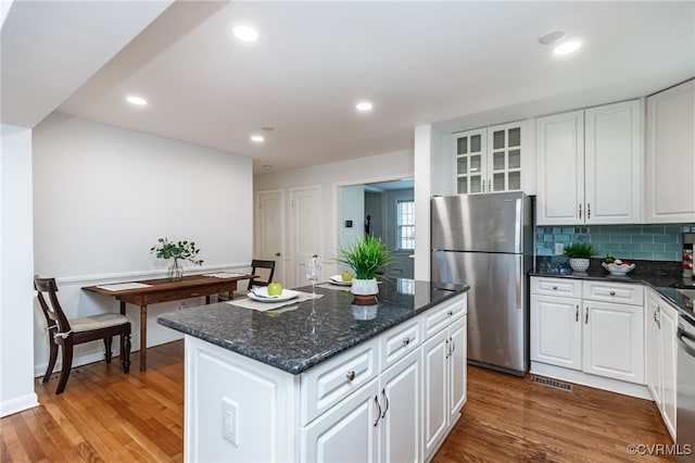 kitchen featuring white cabinetry, appliances with stainless steel finishes, a center island, and hardwood / wood-style floors